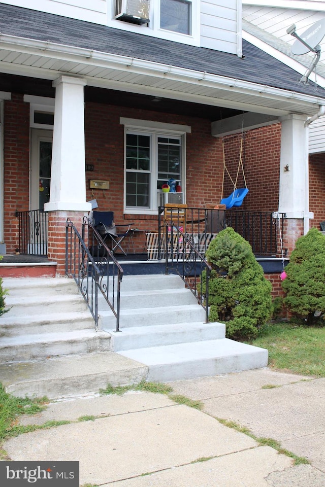 doorway to property featuring brick siding and a porch