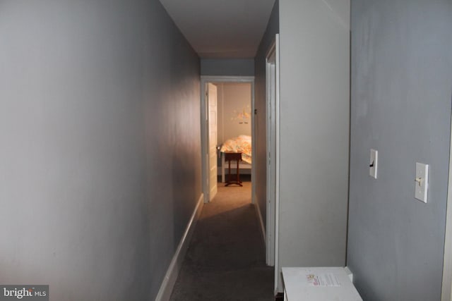 hallway featuring baseboards and carpet