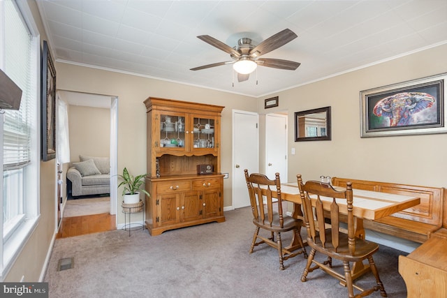 dining room with crown molding, light colored carpet, and ceiling fan