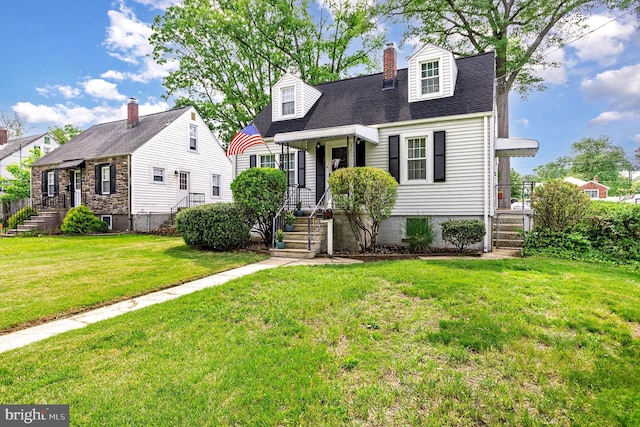 new england style home with a chimney, a front lawn, and roof with shingles