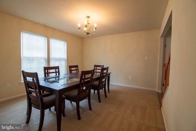 dining area with baseboards, light colored carpet, and a notable chandelier
