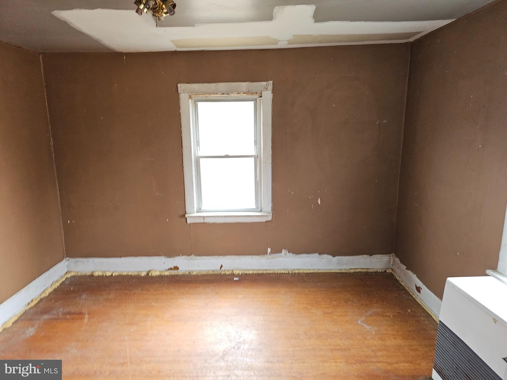 spare room featuring baseboards and wood finished floors