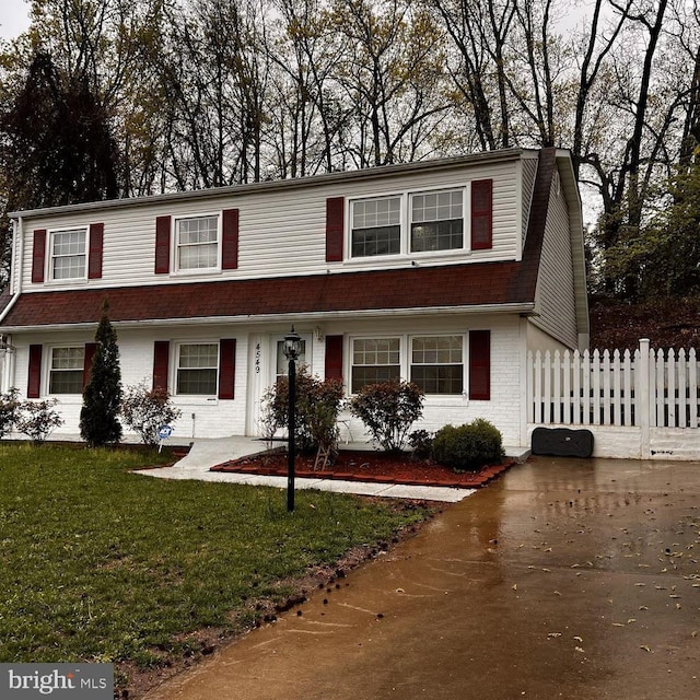view of front of house featuring driveway, a front yard, fence, and brick siding