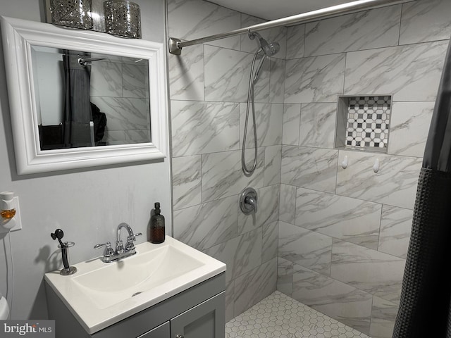 full bath featuring tiled shower and vanity