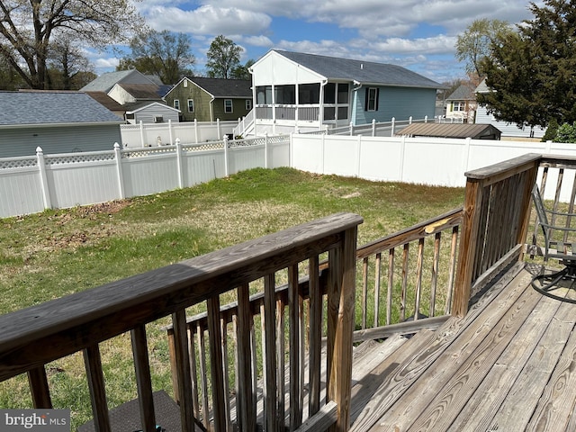 deck featuring a fenced backyard, a residential view, a sunroom, and a lawn