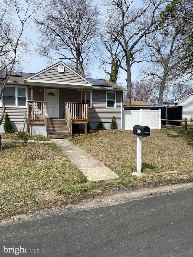view of front of home with a porch, solar panels, and a front lawn