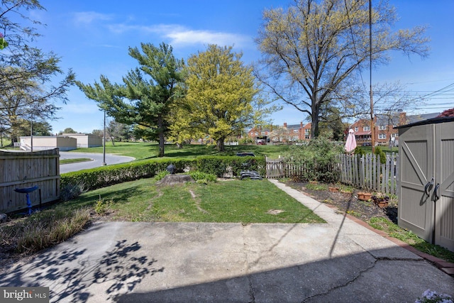 view of yard featuring a storage unit, a patio area, an outbuilding, and fence
