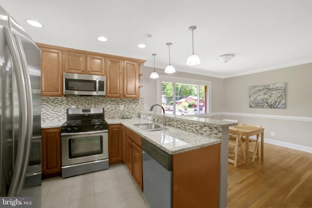 kitchen featuring appliances with stainless steel finishes, a sink, a peninsula, tasteful backsplash, and crown molding