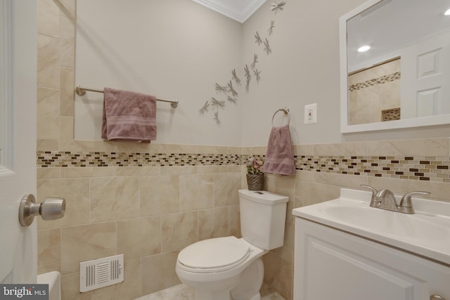 bathroom featuring tile walls, toilet, crown molding, vanity, and a wainscoted wall