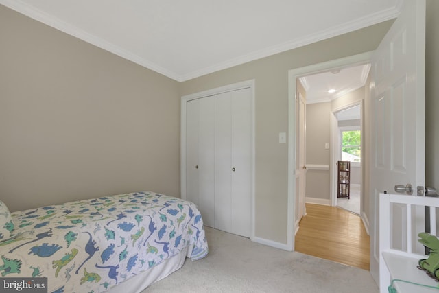 bedroom with ornamental molding, a closet, light colored carpet, and baseboards