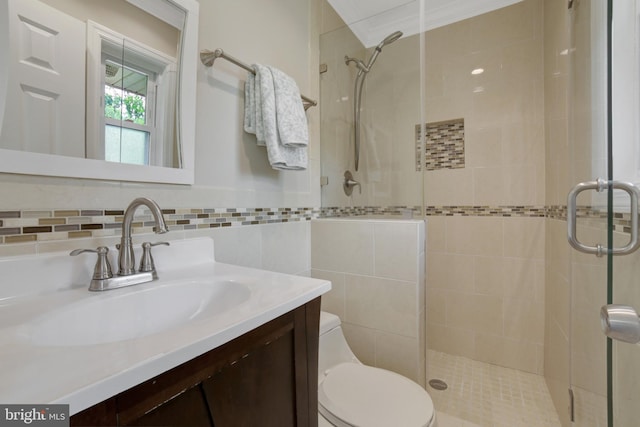 bathroom with a stall shower, toilet, vanity, and tile walls