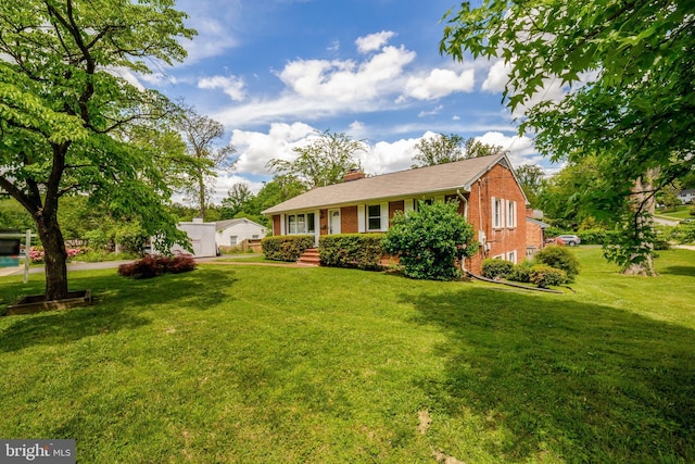 ranch-style home with brick siding, a chimney, and a front yard