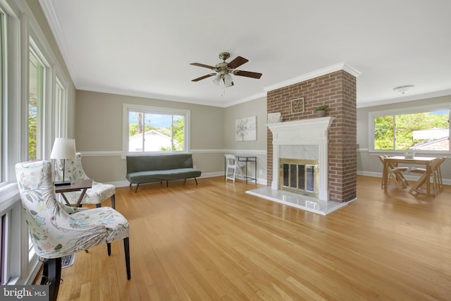 living area with healthy amount of natural light, light wood-type flooring, ornamental molding, and baseboards