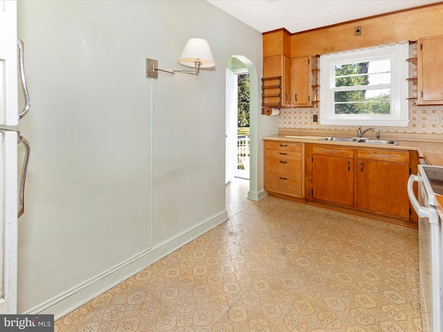268 Magothy Bridge Rd, Pasadena, MD 21122 - kitchen with a sink, light countertops, arched walkways, range, and decorative backsplash