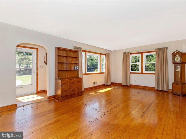 268 Magothy Bridge Rd, Pasadena, MD 21122 - unfurnished living room featuring arched walkways, baseboards, and light wood-style flooring