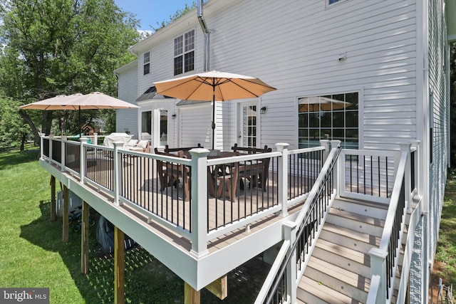 wooden deck with outdoor dining area and a lawn