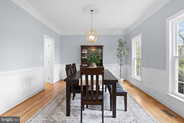 dining area featuring a chandelier, light wood finished floors, ornamental molding, and baseboards