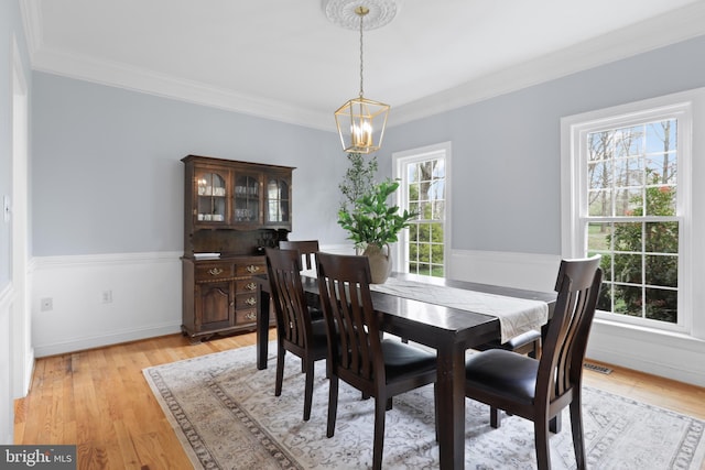 dining room with a chandelier, ornamental molding, light wood-style flooring, and baseboards