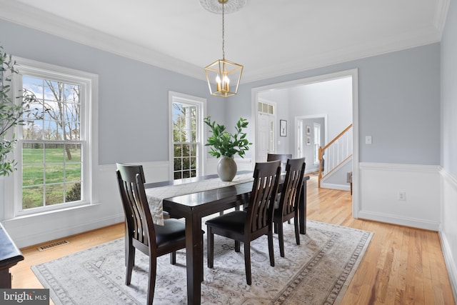 dining area with a chandelier, stairs, plenty of natural light, ornamental molding, and light wood-style flooring
