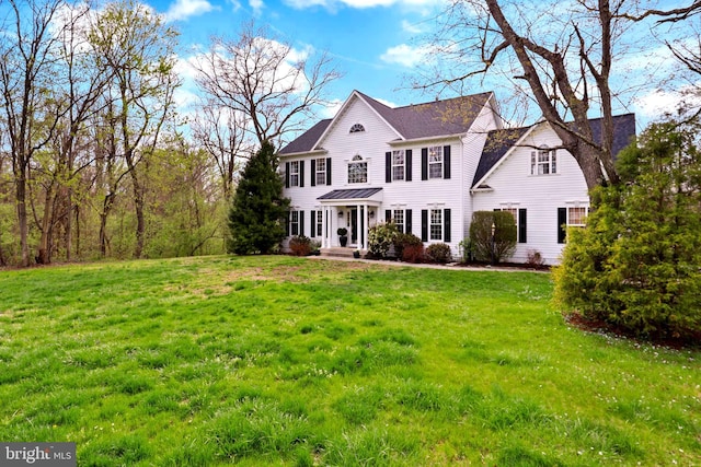colonial-style house featuring a front lawn and a standing seam roof