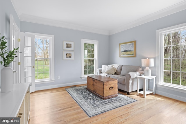 living room featuring baseboards, healthy amount of natural light, light wood-style floors, and ornamental molding