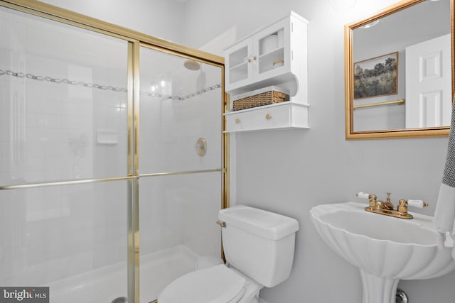 bathroom featuring a shower stall, toilet, and a sink