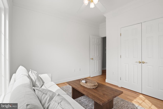 living area with crown molding, a ceiling fan, light wood-style floors, and baseboards
