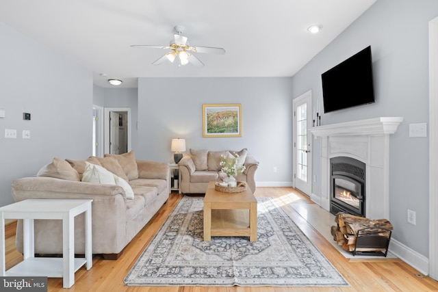 living area with ceiling fan, wood finished floors, a fireplace with flush hearth, and baseboards