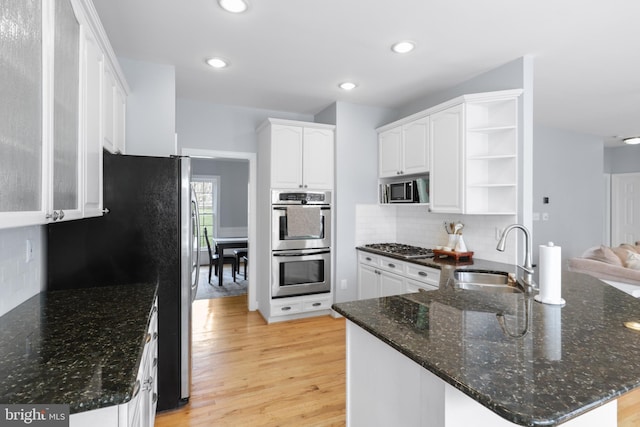 kitchen featuring a sink, stainless steel appliances, open shelves, a peninsula, and white cabinets