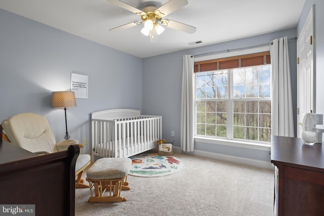 bedroom featuring carpet flooring, baseboards, a nursery area, and ceiling fan
