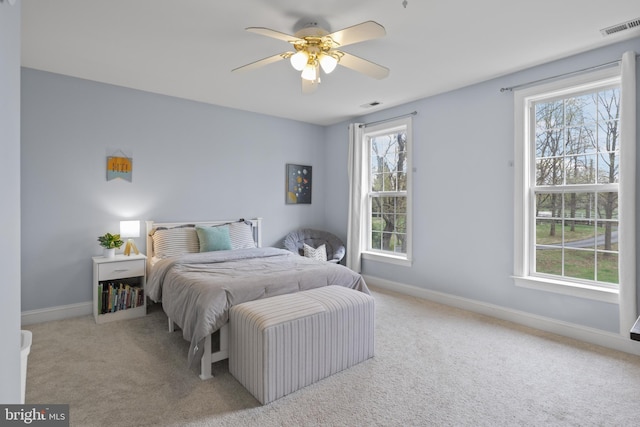 carpeted bedroom featuring multiple windows, baseboards, and a ceiling fan