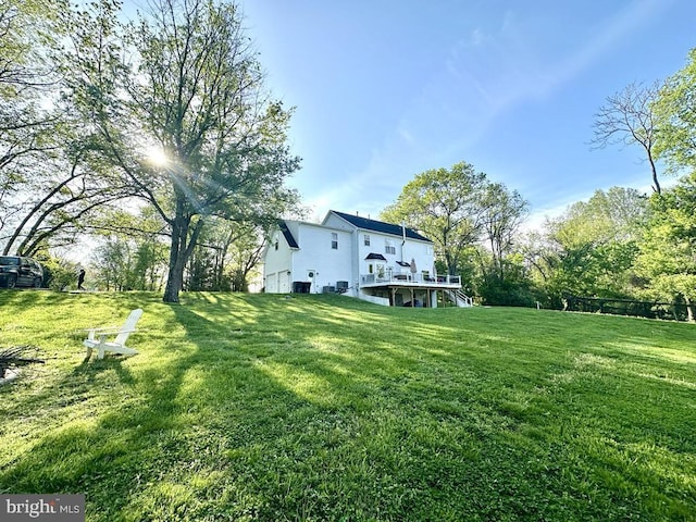 view of green lawn featuring a wooden deck, stairs, and an attached garage