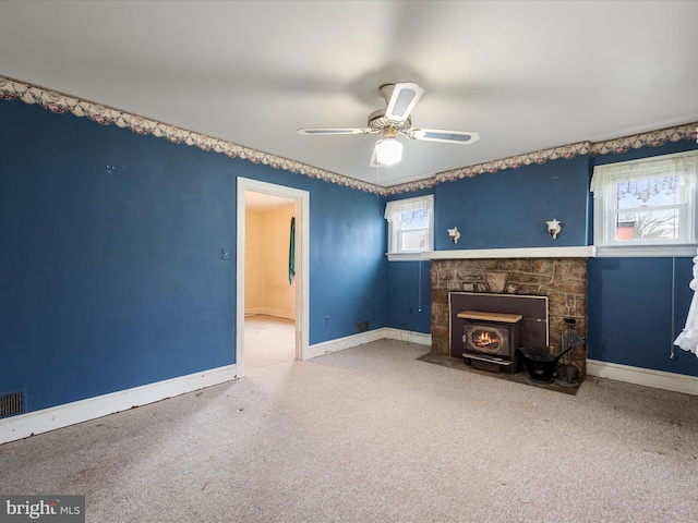 unfurnished living room featuring carpet flooring, ceiling fan, baseboards, and a fireplace