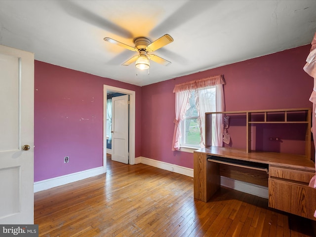 unfurnished office with wood-type flooring, ceiling fan, and baseboards