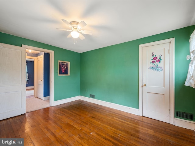 unfurnished room featuring baseboards, a ceiling fan, visible vents, and hardwood / wood-style flooring
