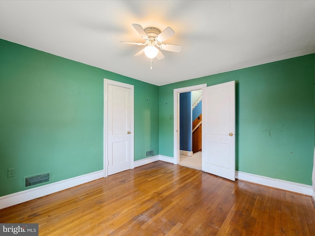 unfurnished bedroom with visible vents, baseboards, hardwood / wood-style floors, and ceiling fan