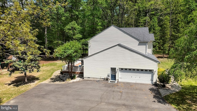 419 Kimberly Way, Felton, DE 19943 - view of side of property with driveway, a garage, a wooden deck, a shingled roof, and a forest view