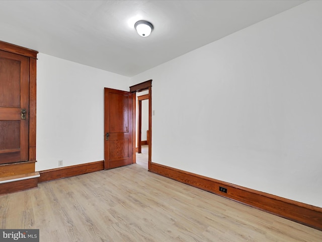 spare room with baseboards and light wood-style floors