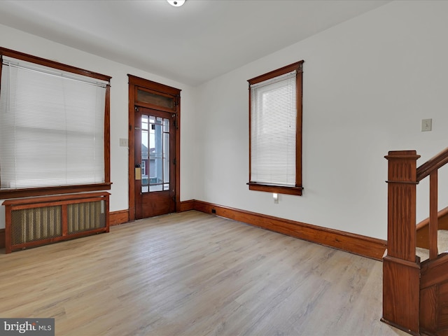 entryway featuring radiator heating unit, stairway, wood finished floors, and baseboards