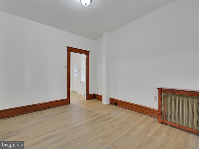 empty room with baseboards, radiator, and wood finished floors
