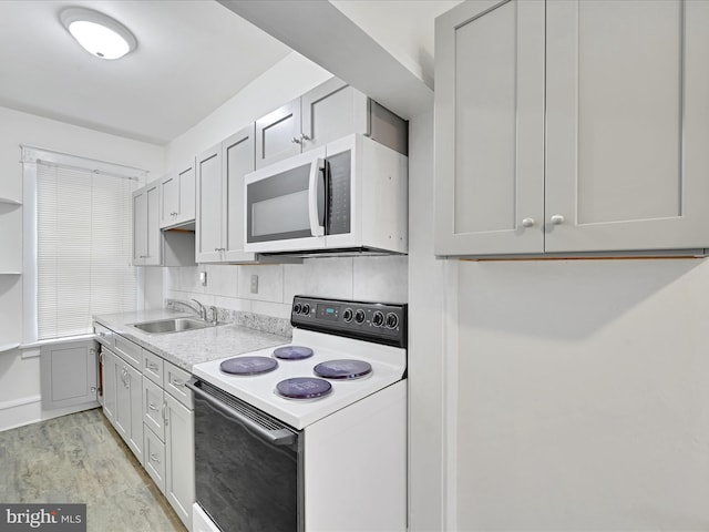 kitchen with white appliances, light countertops, a sink, and light wood finished floors