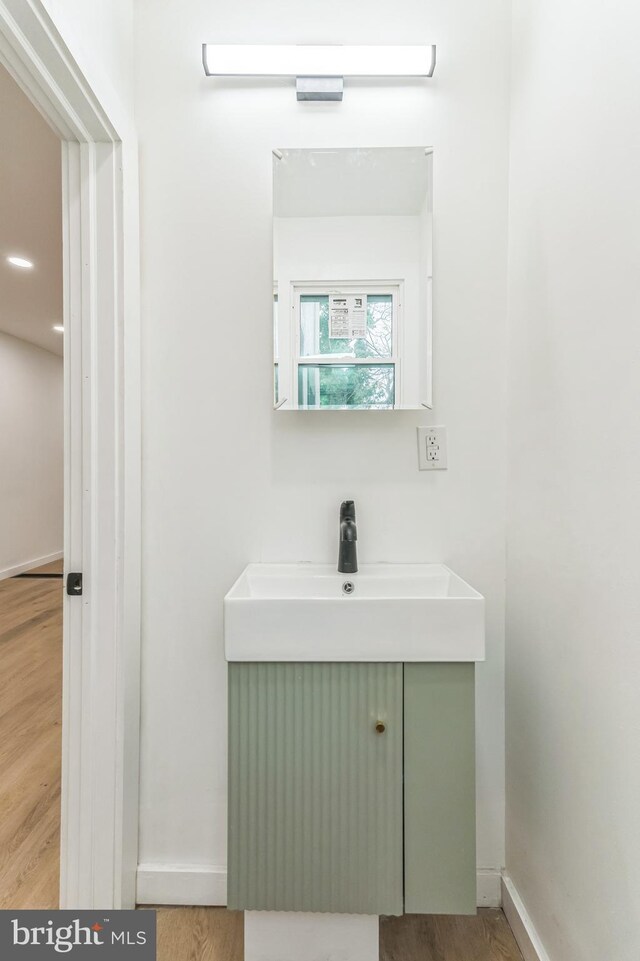 bathroom with wood finished floors, baseboards, and a sink