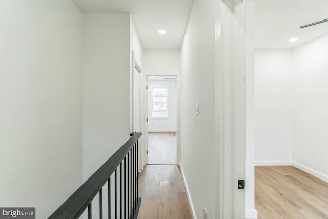 corridor with recessed lighting, wood finished floors, baseboards, and an upstairs landing