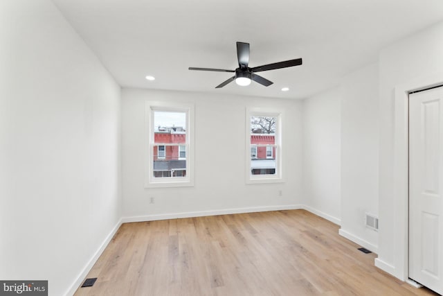unfurnished room featuring light wood-type flooring, visible vents, a ceiling fan, and baseboards