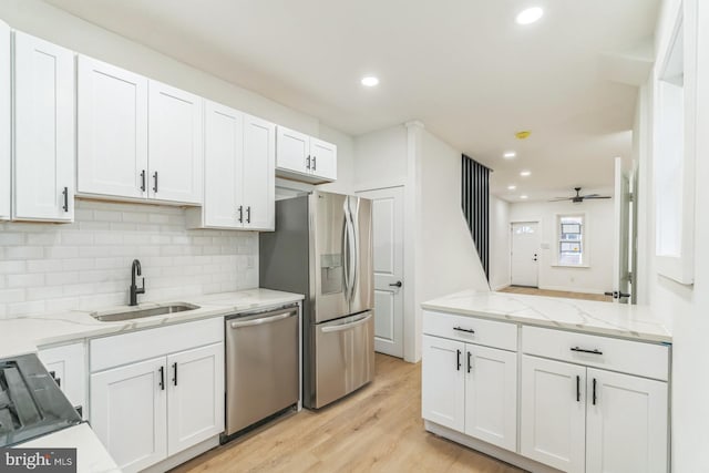 kitchen with stainless steel appliances, a sink, white cabinetry, and tasteful backsplash
