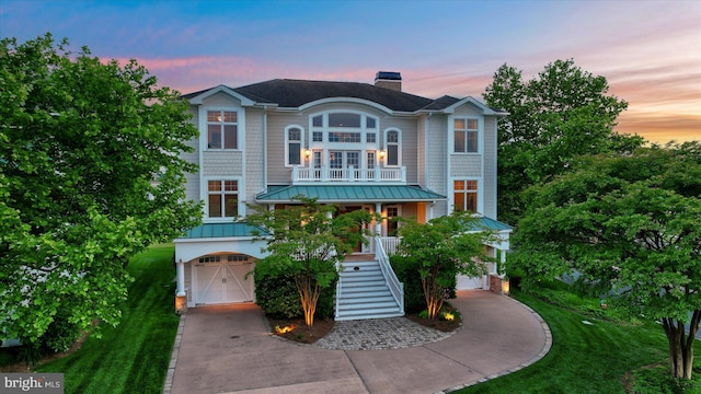coastal inspired home with a chimney, driveway, stairs, a garage, and covered porch