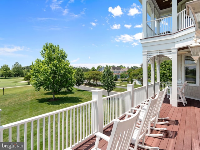 wooden deck with golf course view and a lawn