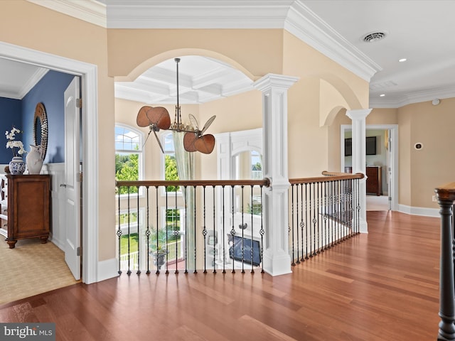 corridor with ornamental molding, visible vents, a notable chandelier, and wood finished floors