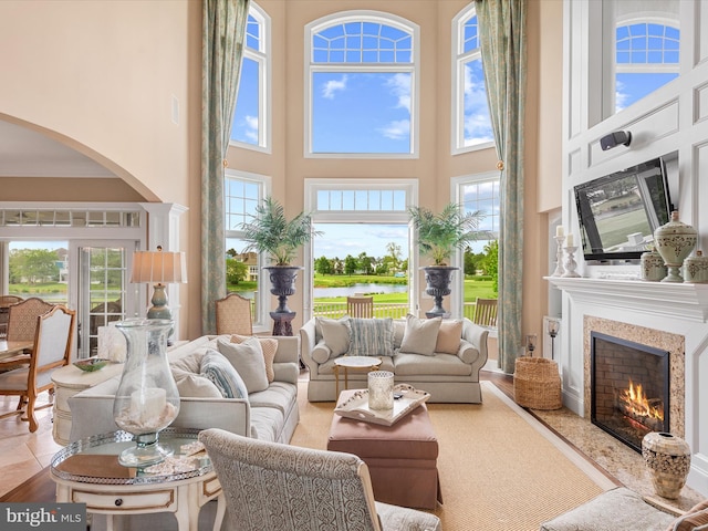 living room with arched walkways, a high ceiling, and a premium fireplace