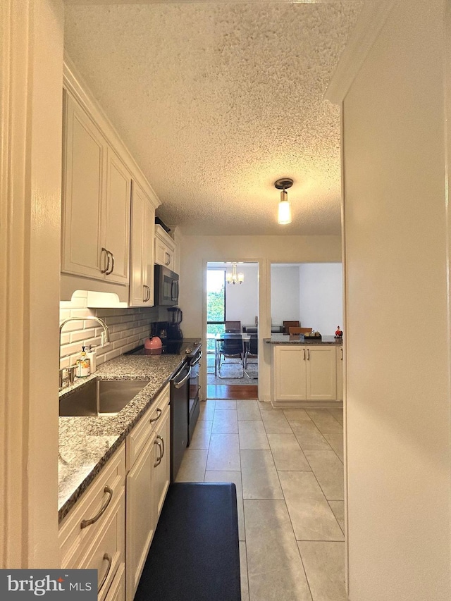 2300 Pimmit Dr Unit 601, Falls Church, VA 22043 - kitchen featuring white cabinets, a sink, tasteful backsplash, light stone counters, and black microwave